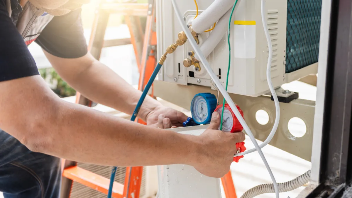 HVAC technician checking gauges on air conditioning equipment