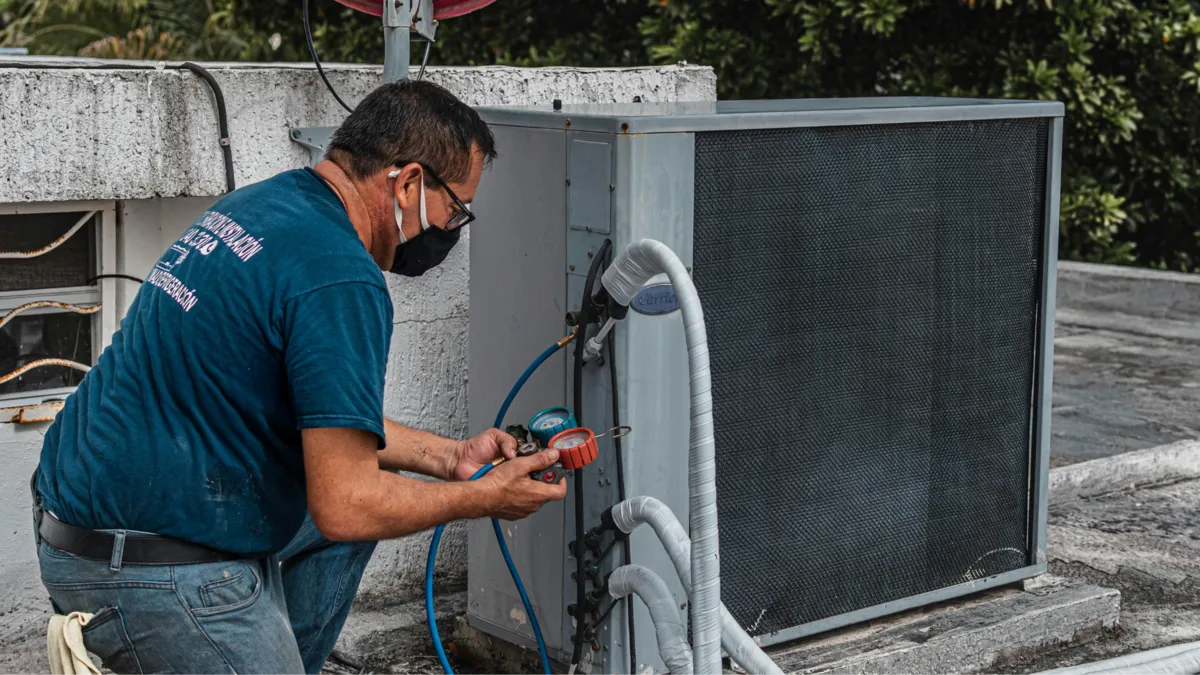 HVAC technician servicing an outdoor air conditioning unit